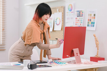 Wall Mural - a creative female graphic designer is concentrating on the computer screen to design, code, and prog