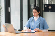 © PRIME STOCK LAB - A concentrated female doctor or nurse is working online with a laptop while sitting at a desk in a hospital consultation room. medicine, technology and healthcare concept