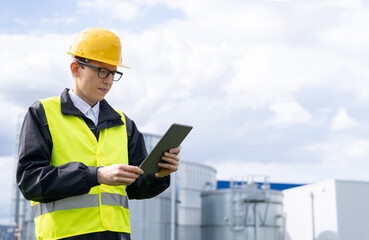 Wall Mural - Engineer with digital tablet on a background of gas tanks	