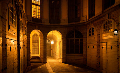 Wall Mural - Entrance to courtyard, arch, and doors of historic French building, illuminated by the light at night in Lyon, France