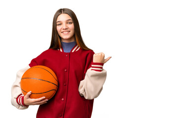 Wall Mural - Teenager girl playing basketball over isolated chroma key background pointing to the side to present a product