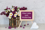 Fototapeta  - Muttertagskarte: Tafel mit dem Text Alles Liebe zum Muttertag vor einem Blumenarrangement mit Flieder und Margeriten.