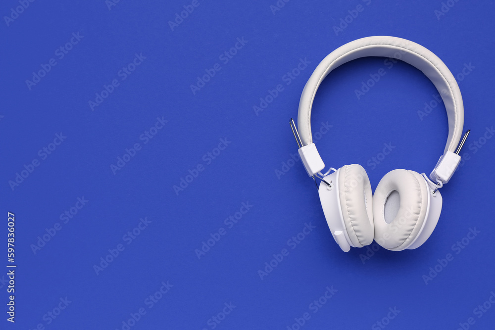 Modern white headphones on blue background