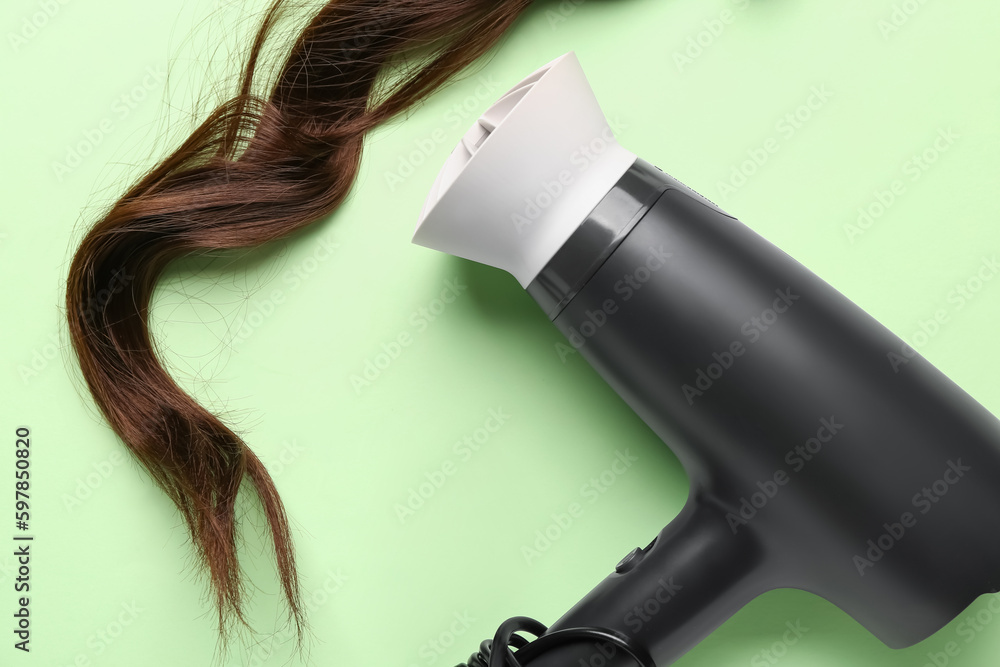 Brown hair with dryer on green background