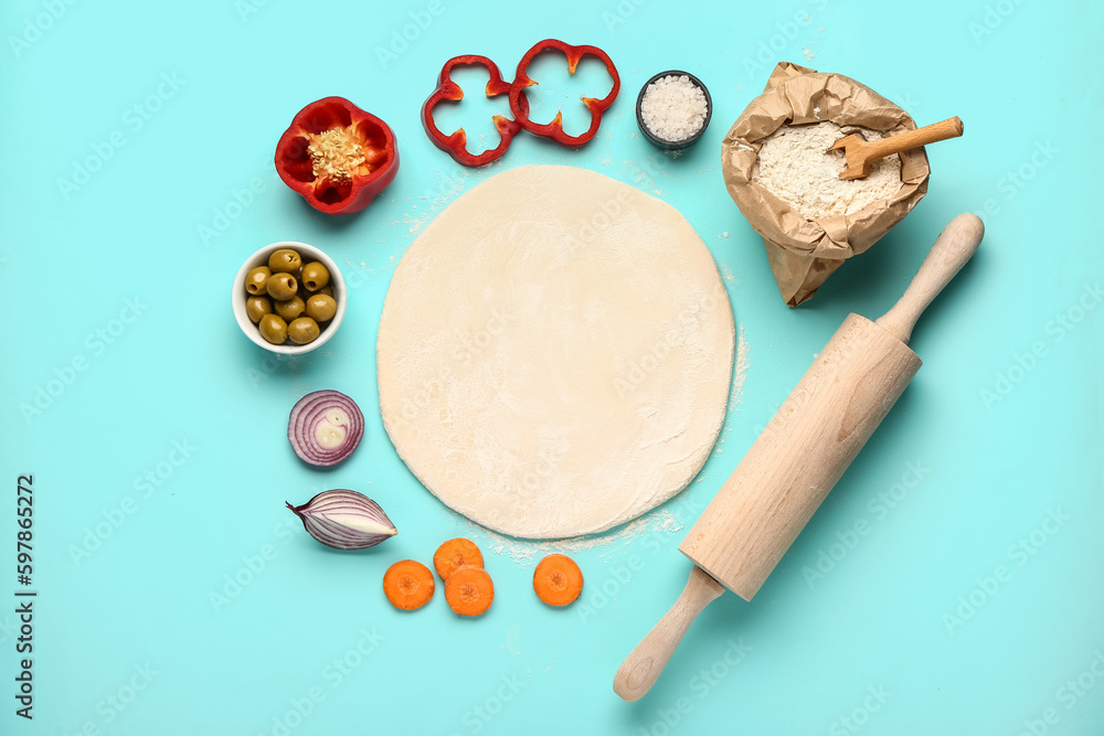 Raw dough and ingredients for preparing vegetable pie on blue background