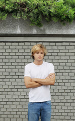 Wall Mural - Young man  standing near a brick wall