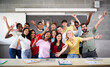 Portrait of a cheerful group of students celebrating in class looking at the camera. Happy Young college people of different ethnicities posing for a photo in the classroom hands up High quality photo