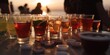 © Alan - cold alcohol drinks and beer glasses close up, blurred beach party at the background at sunset, generative AI