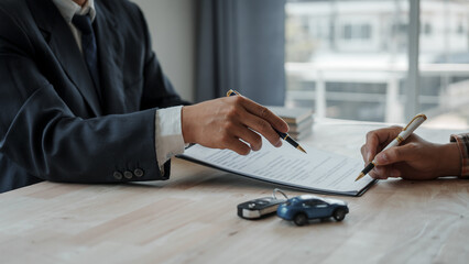 Closeup asian male people car salesman or sales manager offers to sell a car and explains and reads the terms of signing a car contract and insurance.