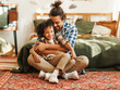 © JenkoAtaman - Happy afro american family father and son laughing and playing while sitting on bed at home.