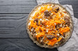 Traditional oriental pilaf with lamb topped with caramelized carrots, raisins and nuts close-up on a platter on a wooden table. horizontal top view from above