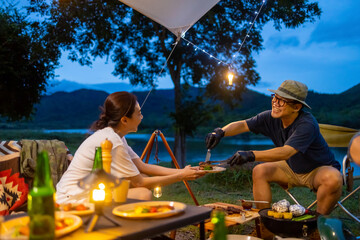 Group of Happy Asian people friends enjoy and fun outdoor lifestyle hiking and camping together on holiday travel vacation. Man and woman couple having dinner together near the tent at summer night.