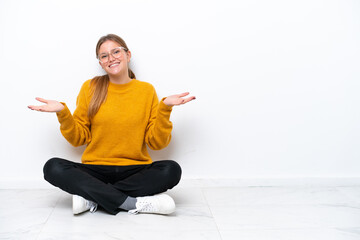 Wall Mural - Young caucasian woman sitting on the floor isolated on white background with shocked facial expression