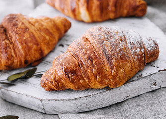 Close up freshly baked croissants with sugar powder on a wooden desk