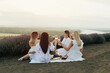 © eduard - Girlfriends having fun and enjoying a picnic in the lavender field. Nature holidays at sunset. Girls clink glasses of wine.