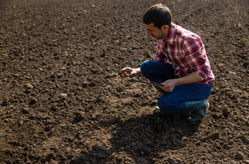 Wall Mural - Male farmer in the field checks the soil. Selective focus.