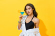 © Atstock Productions - Sexy Asian woman wearing summer swimsuit and spa bathrobe holding cocktail drink in yellow color isolated background studio shot