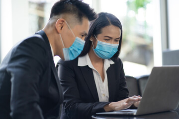 Wall Mural - Two business colleagues at meeting in modern office interior. Businessman and businesswoman discussing work and using laptop computer in meeting indoors.