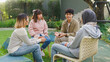 © tirachard - Small Asian group of people sit in a close circle and talk to a therapist in park. Smile people sharing story happy speak diverse people sitting in circle at group therapy session with psychologist.