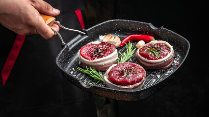 Wall Mural - Chef cooking steak on grill pan with rosemary and spices. Beef medallions wrapped in bacon. Culinary, cooking concept, Long banner format