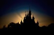 Silhouette of a magic castle with sun rays and gradient sky.