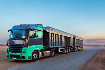 Canvas Print - Duo-trailer with tippers for scrap metal parked at sunset next to a road in the countryside.