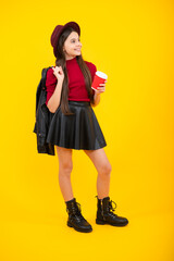 Poster - Happy teenager portrait. Teenager girl holding a hot cup of coffee or tea. Child with takeaway cup on yellow background, morning energy drink beverage. Smiling girl.