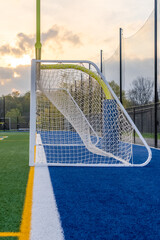 Wall Mural - Dramatic late afternoon photo of a integrated soccer and football goal on a synthetic turf field before a night game.
