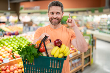 Wall Mural - Man with fruits and vegetables at grocery store. Healthy food for mens health. Man with shopping cart full of fresh vegetables. Man at grocery store or supermarket.