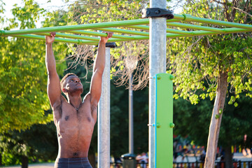 Poster - Young fit shirtless black man exercising on monkey bars outdoors on sunny summer day. Fitness and sport lifestyle.