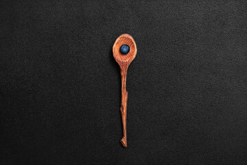 Wall Mural - Fresh blueberry in a wooden spoon. Berry on a black background. View from above.