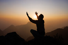 Silhouette Of A Man Is Praying To God On The Mountain. Praying Hands With Faith In Religion And Belief In God On Blessing Background. Power Of Hope Or Love And Devotion.