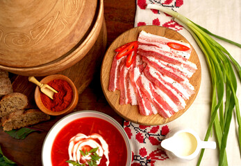 Poster - Traditional Ukrainian borsht, red vegetable soup or borscht with smetana on wooden background. Slavic dish with cabbage, beets, tomatoes Traditional Ukrainian towel along with garlic, bread and salt