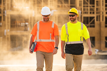 Two construction workers with hardhat helmet on construction site. Construction engineer workers in builder uniform. Two builders ready to build new house. Workers in hardhat at construction site.