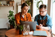 © Drobot Dean - Young woman using laptop while training man with down syndrome to work in cafe
