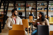 © Drobot Dean - Indian man and woman students talking and drinking coffee while sitting in library