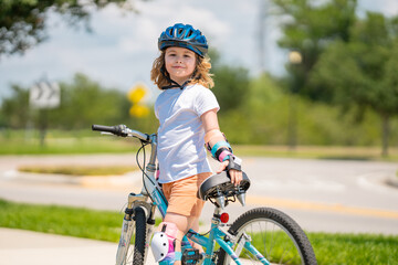 Poster - Child riding bicycle. Little kid boy in helmet on bicycle along bikeway. Happy cute little boy riding bicycle. Child in the protective helmet for bike cycling on bicycle.