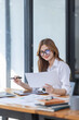 © David - Asian Business woman using calculator and laptop at workplace doing math finance on an office desk, tax, report, accounting, statistics, and analytical research concept
