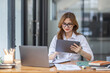 © David - Asian Business woman using calculator and laptop at workplace doing math finance on an office desk, tax, report, accounting, statistics, and analytical research concept
