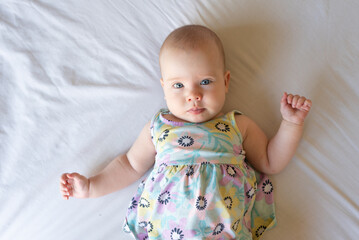 Wall Mural - A top down image of a content and aware baby girl of 4 months old lying on a bed