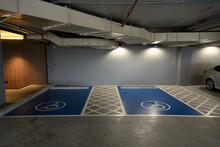 Interior of the underground garage of a modern building construction with parking places for disabled.International handicapped symbol painted in blue floor on a shopping center parking space.