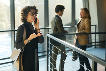 Poster - Confident middle aged businesswoman explaining something to colleague or business partner during conversation on smartphone