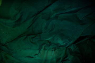 dark image of a wet green rumpled fabric on the water, with beautiful highlights, for your creative 