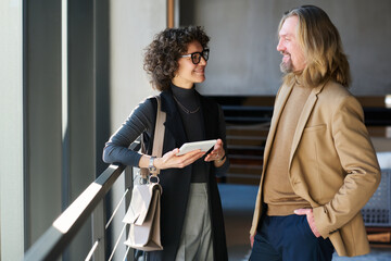 Aufkleber - Two happy entrepreneurs in quit luxury apparel sharing working methods and experience at meeting while one of them using tablet