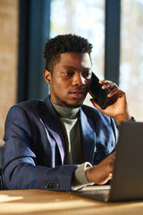 Poster - Young African American male broker talking to client on smartphone and using laptop while analyzing exchange rates on stock market