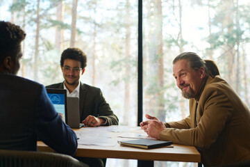 Aufkleber - Smiling mature chief executive officer talking to young male subordinate at working meeting in boardroom while looking at him