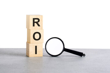 Wall Mural - ROI - Return On Investment - text on wooden cube blocks and magnifying glass on grey table