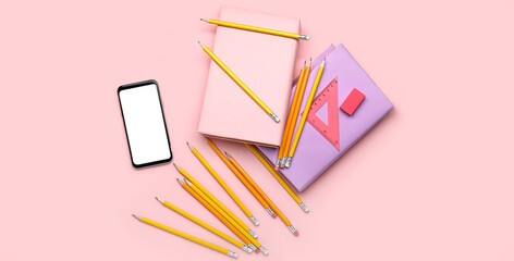 School stationery with books and mobile phone on pink background