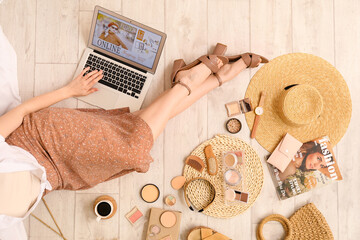 Wall Mural - Woman with laptop and accessories shopping online on light wooden floor