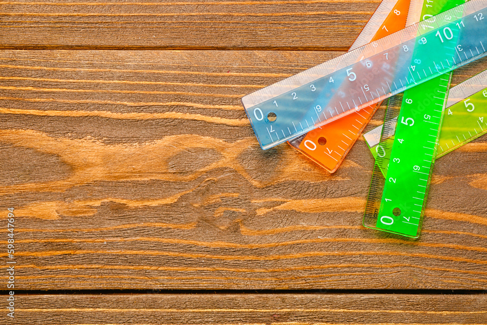 Colorful plastic rulers on wooden background